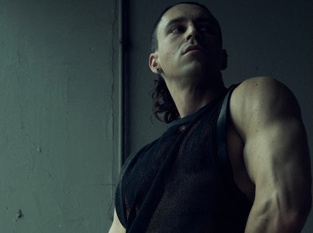 Low-angle front view of the black SYZMIC MESH TANK TOP 211 in textured organic cotton mesh.