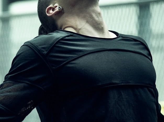Close-up of the curved chest and shoulder panels on the SYZMIC black long-sleeve top.