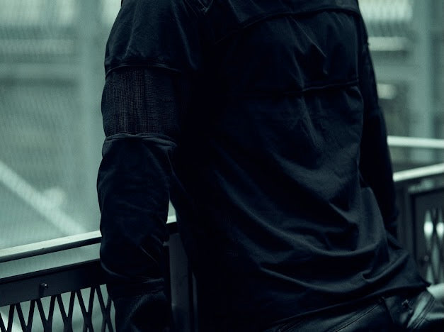 Detail of the layered sleeve panels and contrasting mesh on the SYZMIC black long-sleeve top.