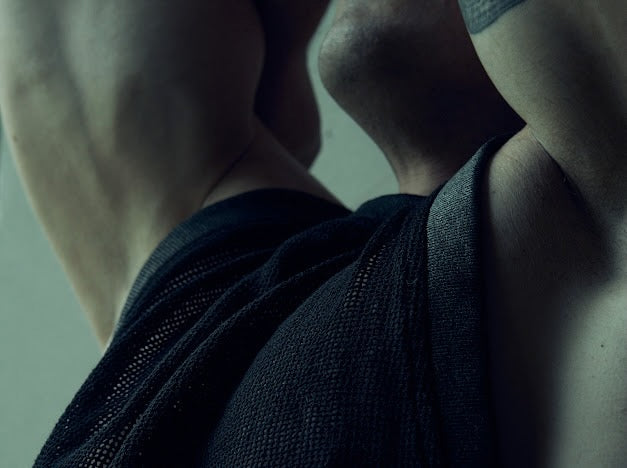Close-up of the black SYZMIC MESH TANK TOP 211 armhole and textured mesh with the model's arm raised.