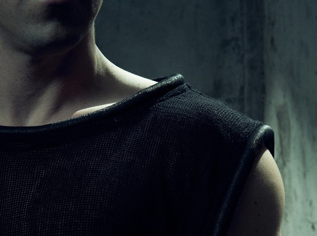 Close-up of the black MESH TANK TOP 212 showing textured cotton mesh and tubular neck trim.