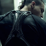 Rear view of the SYZMIC black long-sleeve top, styled beneath a separate black harness.