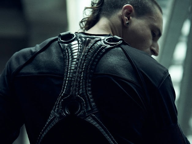 Rear view of the SYZMIC black long-sleeve top, styled beneath a separate black harness.