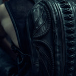 Detail of the raised textures and curved panels on a black SYZMIC backpack.