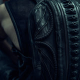 Detail of the raised textures and curved panels on a black SYZMIC backpack.