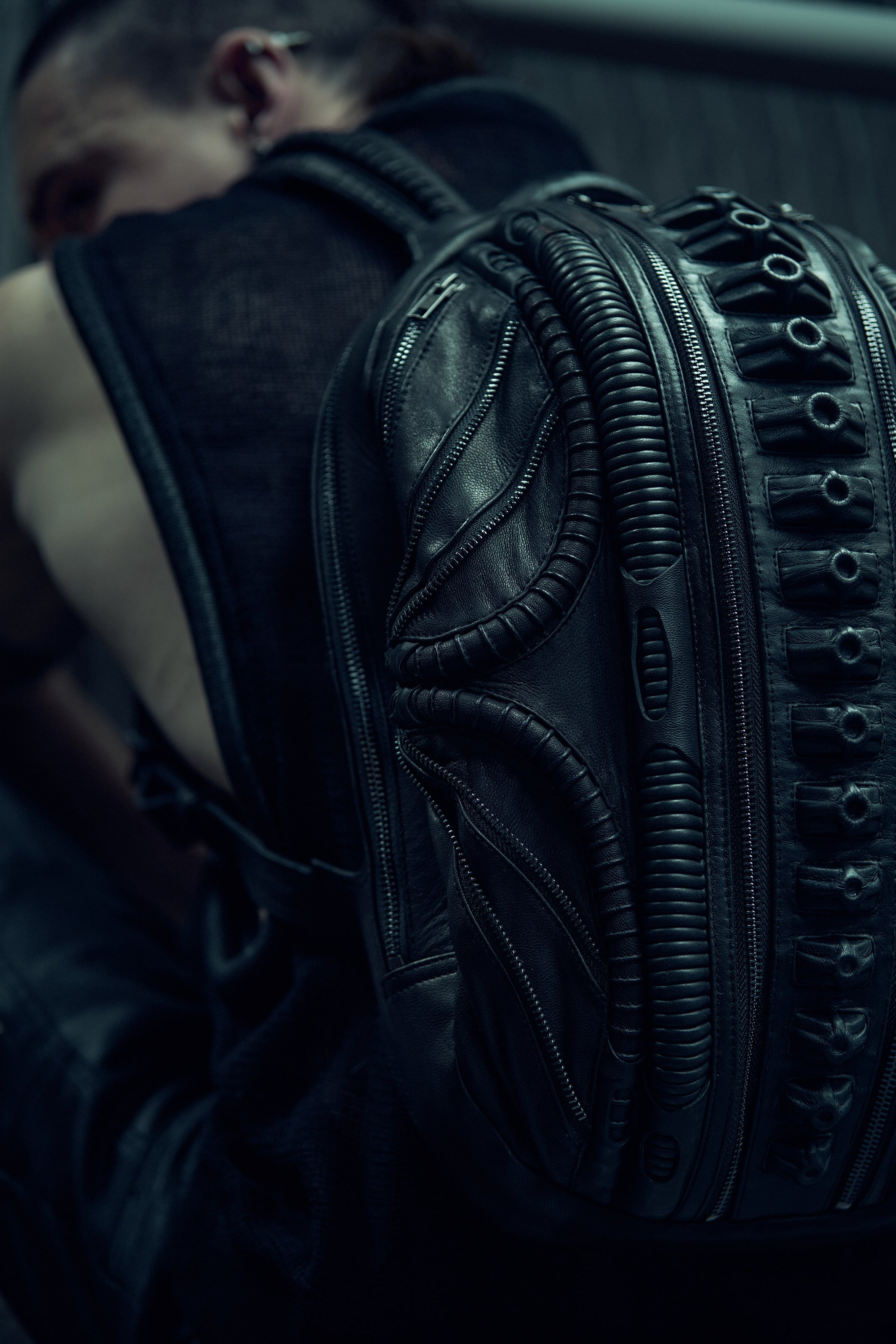 Detail of the raised textures and curved panels on a black SYZMIC backpack.