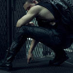 Seated model wearing a black SYZMIC backpack and black mesh tank top.