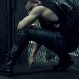 Seated model wearing a black SYZMIC backpack and black mesh tank top.