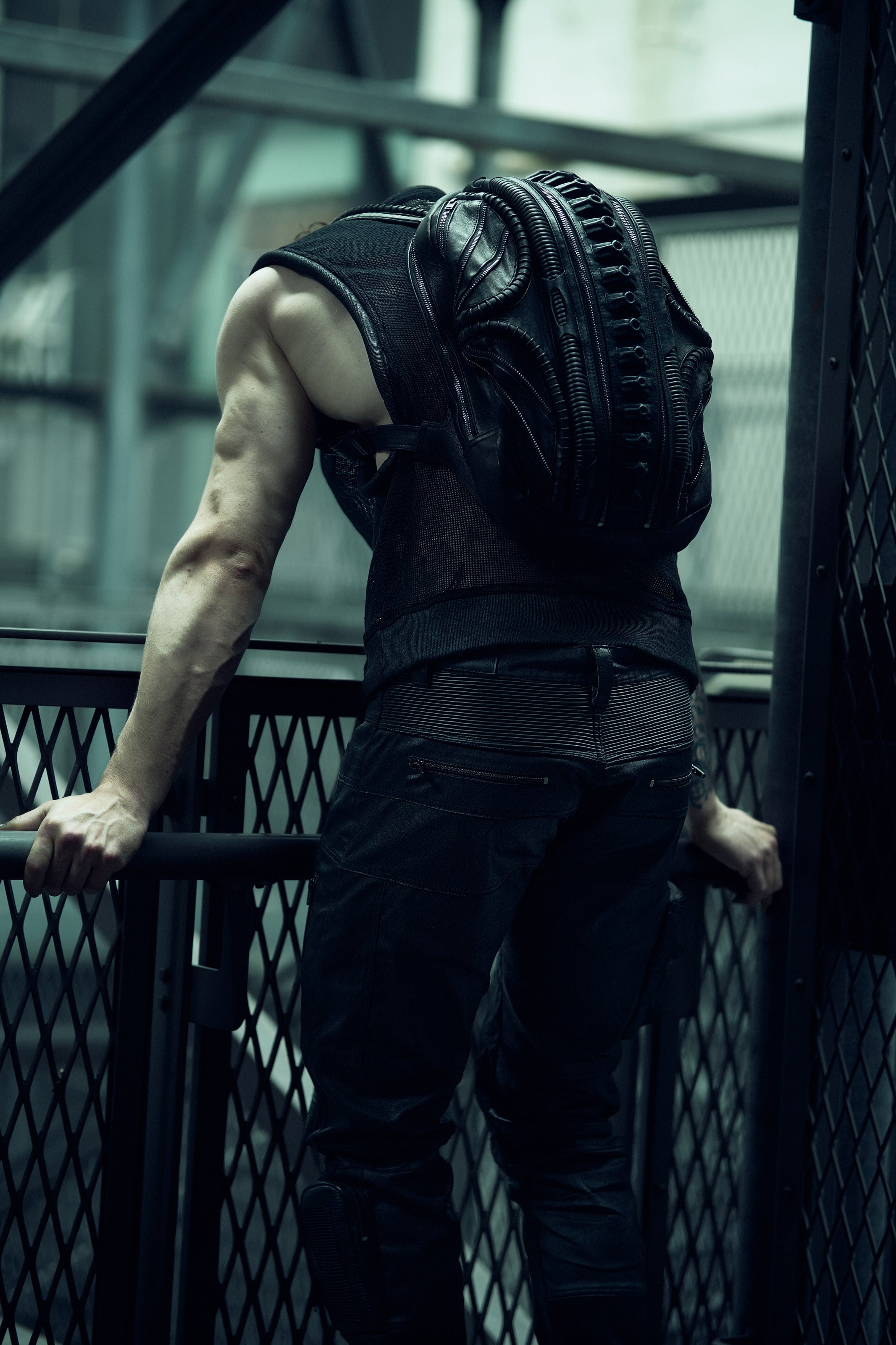 Rear view of a black sculptural SYZMIC backpack worn with a sleeveless top.