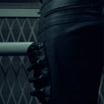 Close-up of black SYZMIC trousers with layered panels and side detailing.