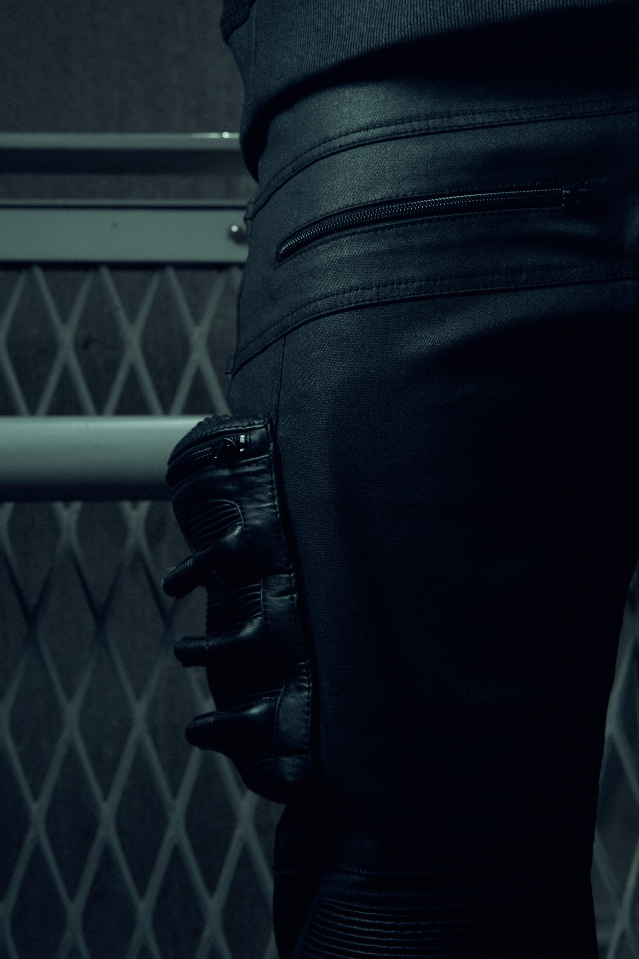 Close-up of black SYZMIC trousers with layered panels and side detailing.