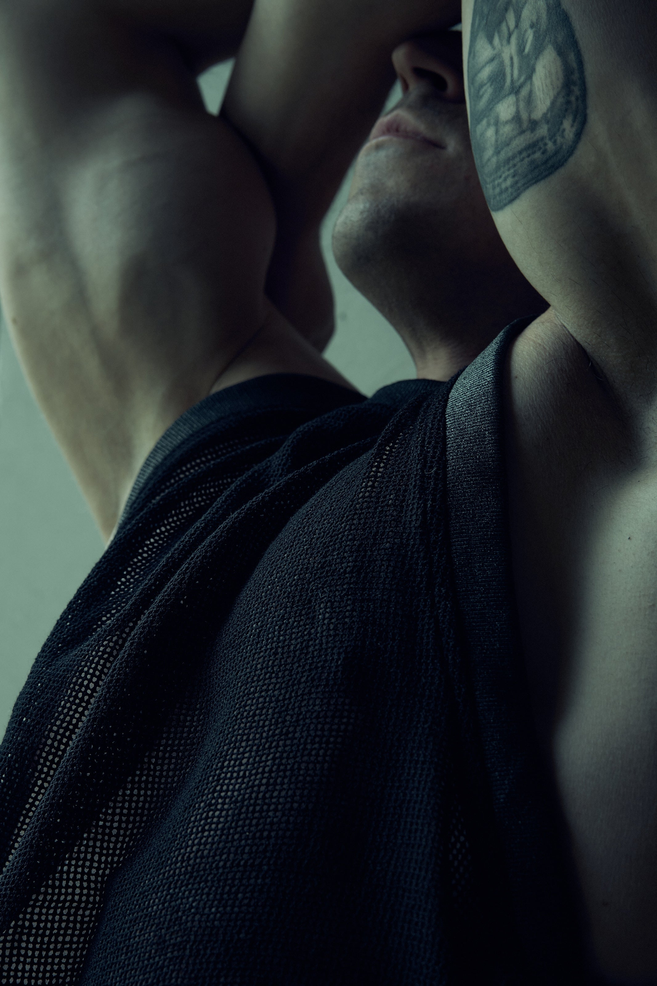Black SYZMIC EIDOS-214 mesh tank top, close-up with the model’s arms raised.