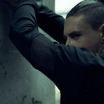 Black SYZMIC EIDOS-215 long-sleeve top, close-up with arms raised.