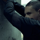 Black SYZMIC EIDOS-215 long-sleeve top, close-up with arms raised.