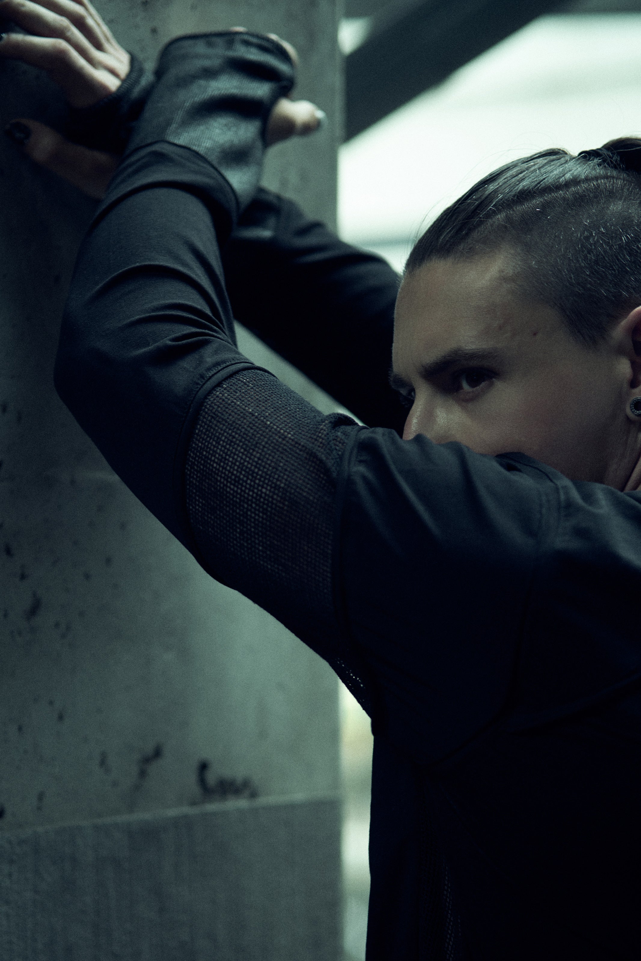 Black SYZMIC EIDOS-215 long-sleeve top, close-up with arms raised.