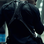 Rear view of the black SYZMIC EIDOS-215 long-sleeve top worn beneath a backpack.