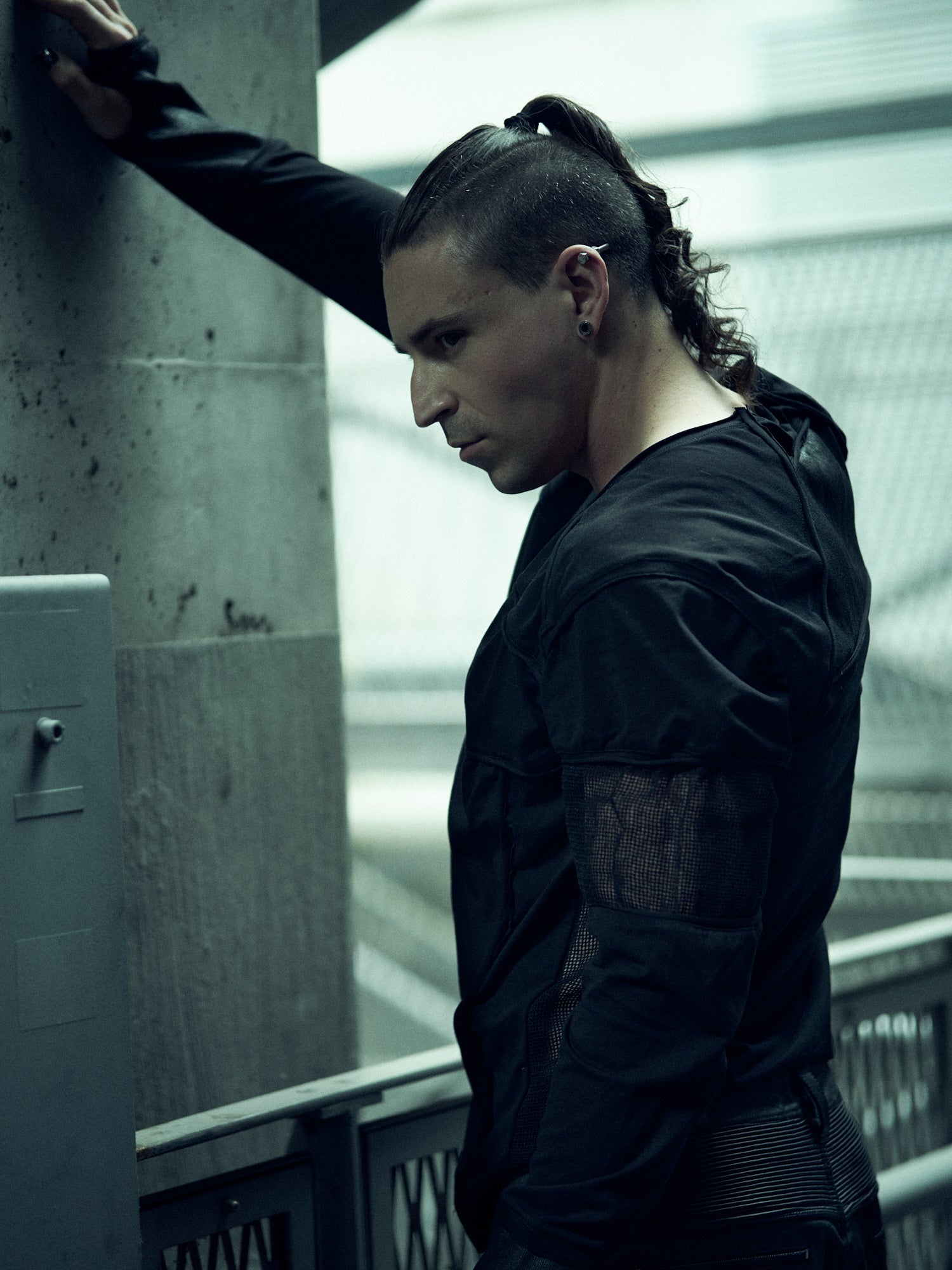 Black SYZMIC EIDOS-215 long-sleeve top, side portrait with one arm raised.