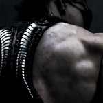 Rear close-up of Flo wearing the black SYZMIC HYLO-501 leather holster bag, showing its sculpted vertebral back panel. Photography by Lazar.