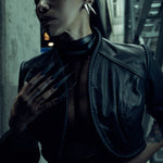 Lily Gatins wearing the black SYZMIC JACKET EIDOS-408, close-up showing the sculpted shoulder panels and coiled trim. Photography by Nox / Lux.