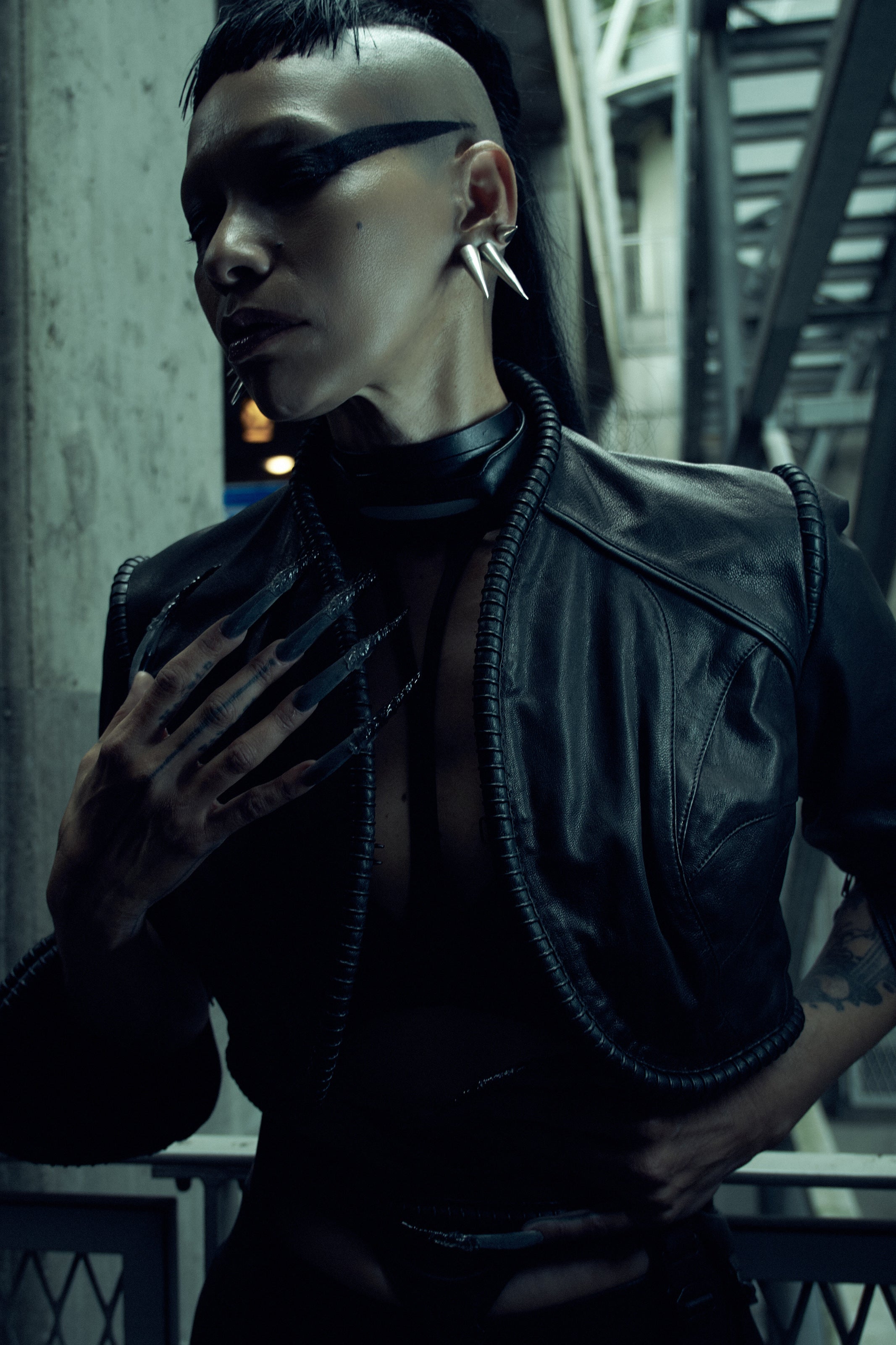Lily Gatins wearing the black SYZMIC JACKET EIDOS-408, close-up showing the sculpted shoulder panels and coiled trim. Photography by Nox / Lux.