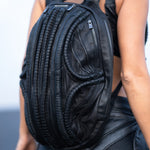 Unisex futuristic leather laptop backpack in post-apocalyptic dark avant-garde fashion on woman